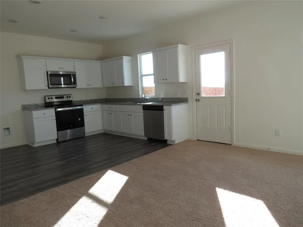 a kitchen with stainless steel appliances granite countertop a stove top oven a sink and dishwasher with wooden floor