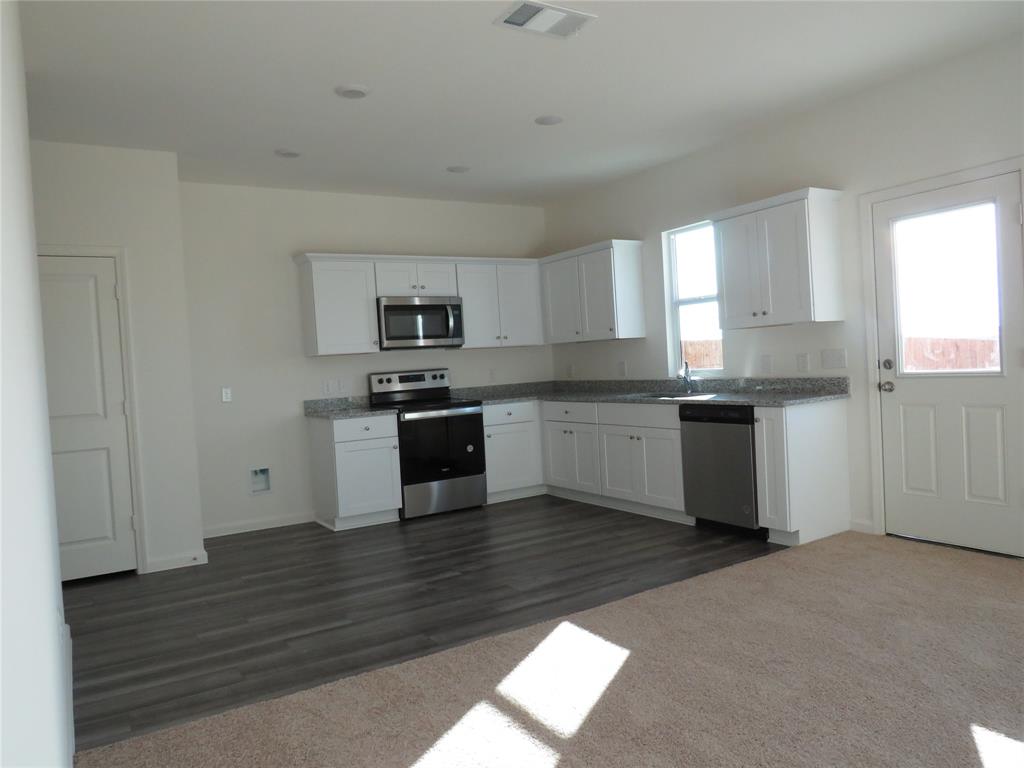 1906 Chapel Hill Road Princeton, TX 75407 - Photo 34 of 36 a kitchen with stainless steel appliances granite countertop a stove top oven a sink and dishwasher with wooden floor