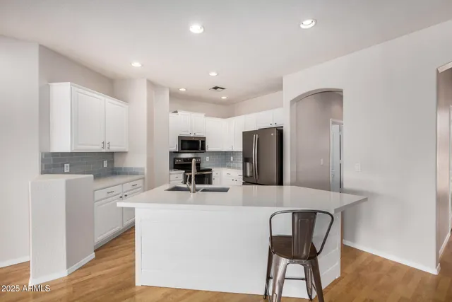 a kitchen with stainless steel appliances kitchen island a refrigerator sink and cabinets