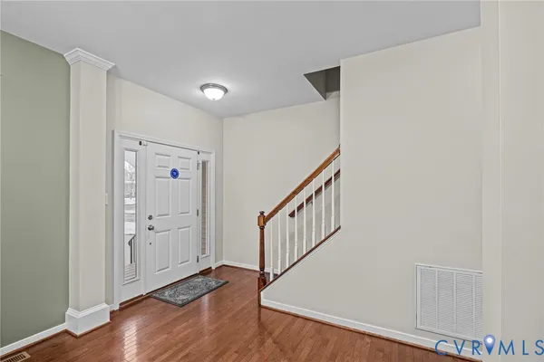 a view of an empty room and kitchen view with wooden floor
