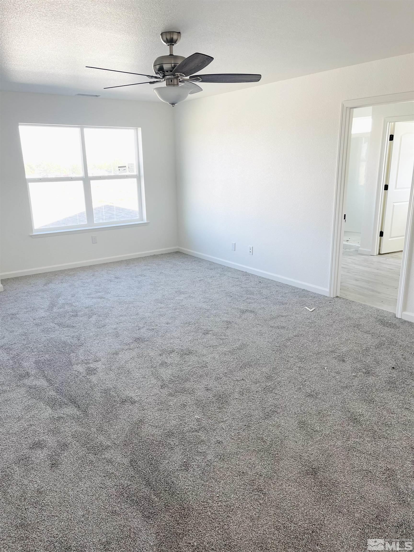 1318 Serenity Circle Fernley, NV 89408 - Photo 4 of 13 an empty room with windows and ceiling fan