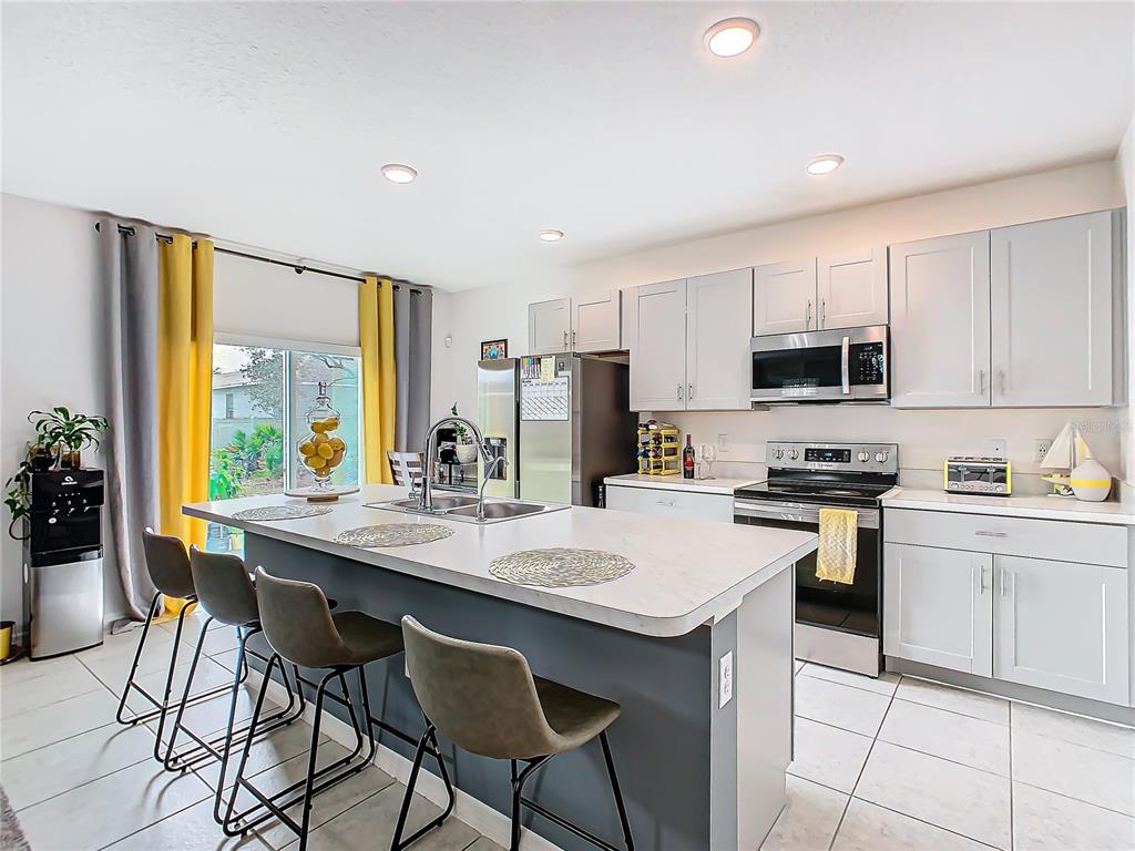 208 Goldenrod Lane Kissimmee, FL 34759 - Photo 17 of 40 a kitchen with a stove a sink a microwave a dining table and chairs