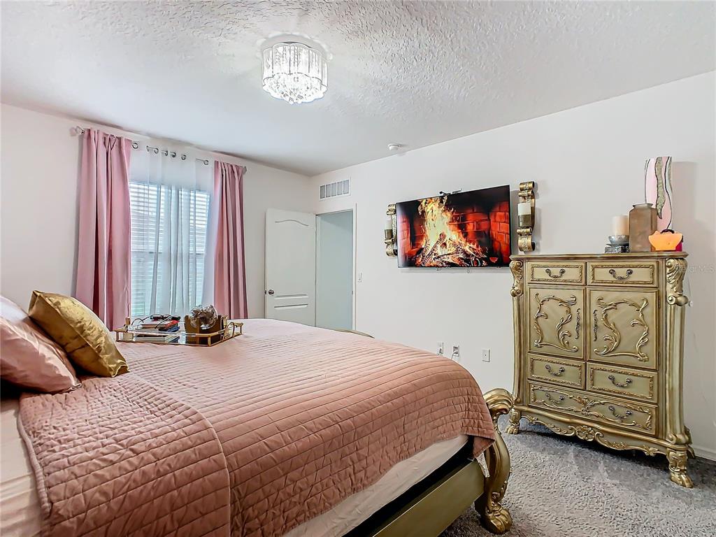 208 Goldenrod Lane Kissimmee, FL 34759 - Photo 21 of 40 a bedroom with a bed a dresser and flat screen tv