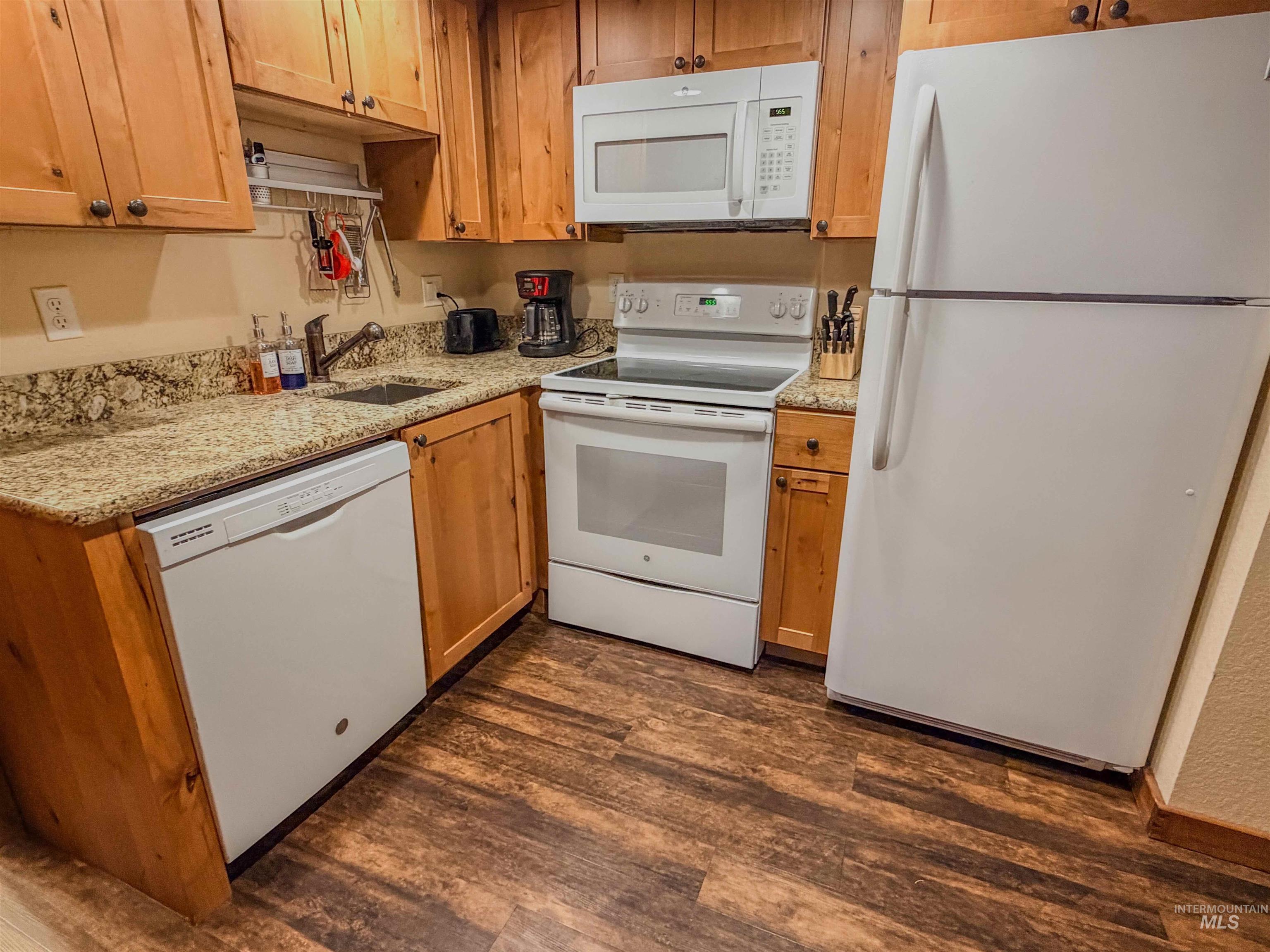 1607 Davis Avenue, Unit C6 McCall, ID 83638 - Photo 12 of 30 Kitchen featuring white appliances, light stone countertops, dark wood finished floors, and brown cabinets