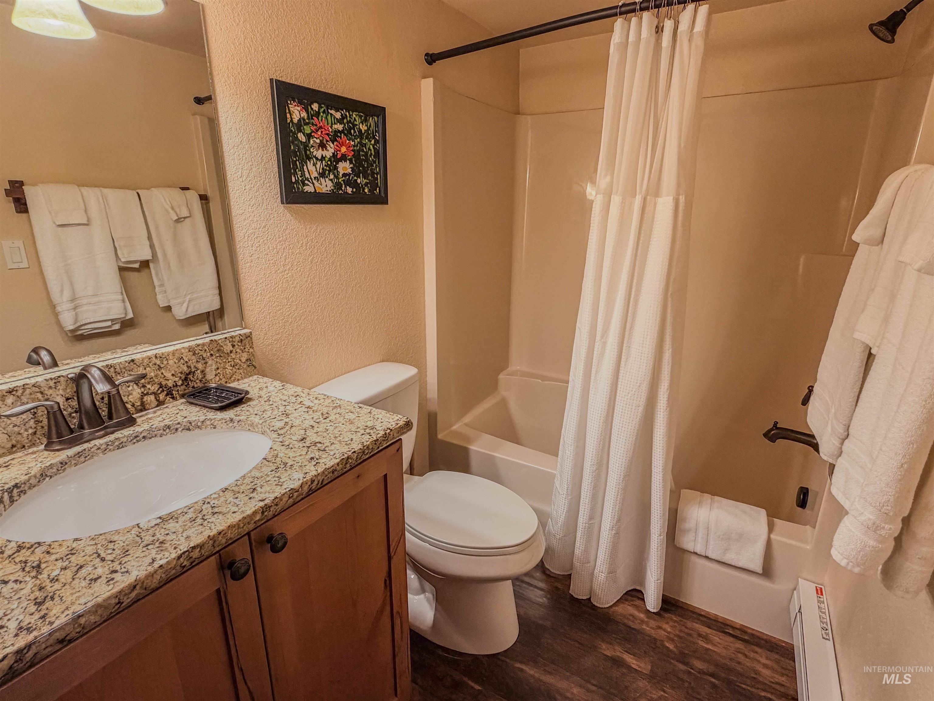 1607 Davis Avenue, Unit C6 McCall, ID 83638 - Photo 17 of 30 Bathroom with a textured wall, shower / bathtub combination with curtain, vanity, dark wood finished floors, and baseboard heating