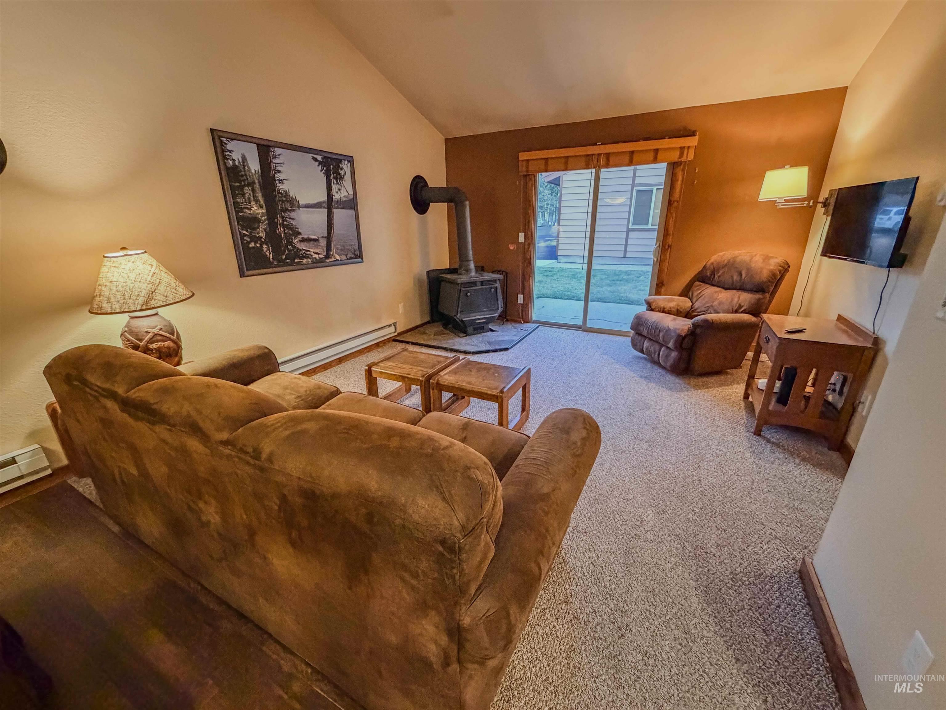 1607 Davis Avenue, Unit C6 McCall, ID 83638 - Photo 2 of 30 Living area featuring a wood stove, baseboard heating, light colored carpet, and vaulted ceiling