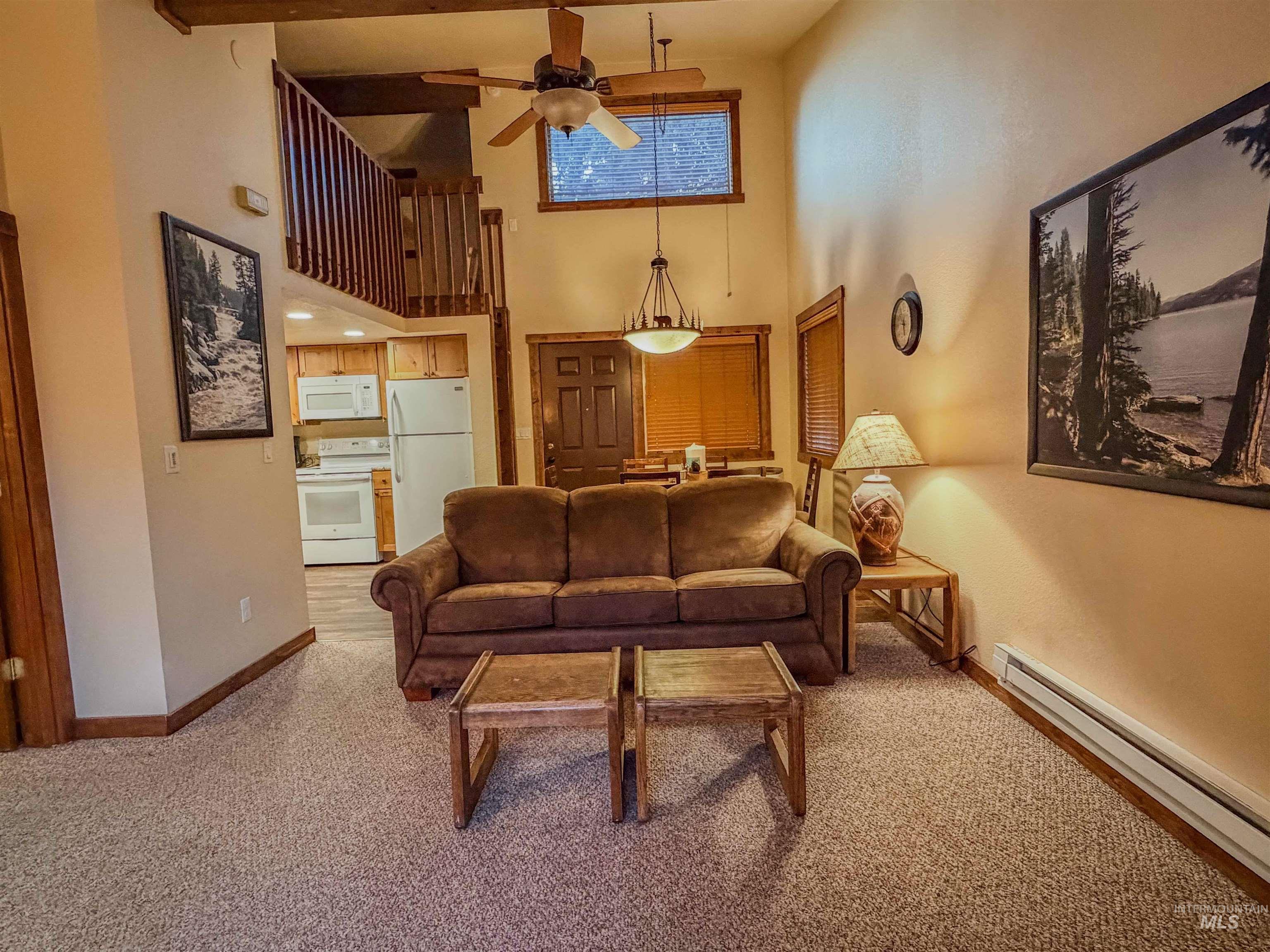 1607 Davis Avenue, Unit C6 McCall, ID 83638 - Photo 5 of 30 Living room with a baseboard heating unit, light colored carpet, a ceiling fan, and a towering ceiling