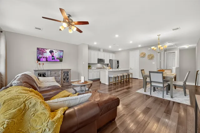 a living room with furniture kitchen view and a wooden floor