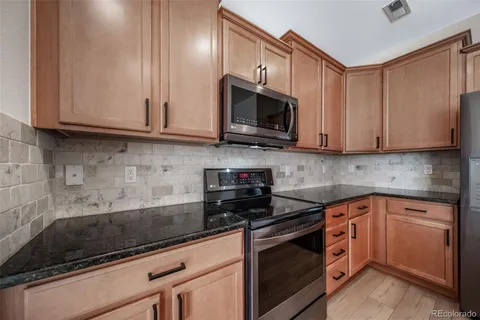 a kitchen with stainless steel appliances granite countertop white cabinets granite counter tops and a wooden floors