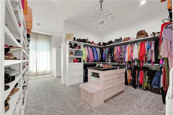 a view of walk in closet with clothes and shoes