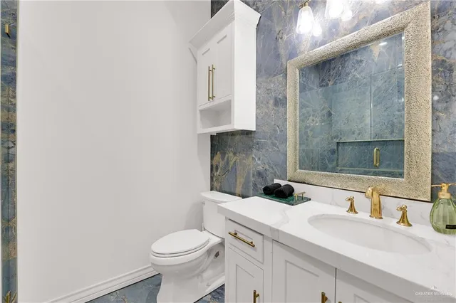 a bathroom with a granite countertop toilet sink and mirror