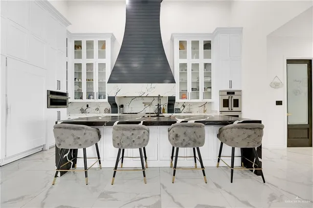 a kitchen with stainless steel appliances kitchen island granite countertop a table chairs and a white cabinets