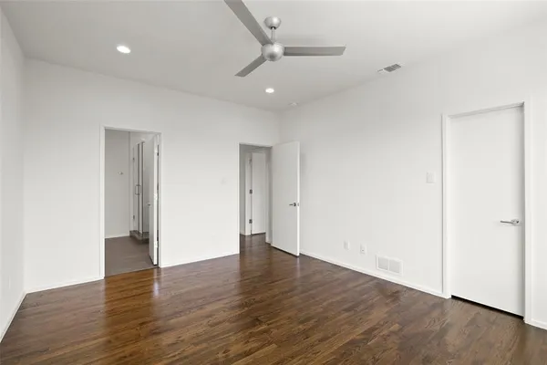an empty room with wooden floor and ceiling fan