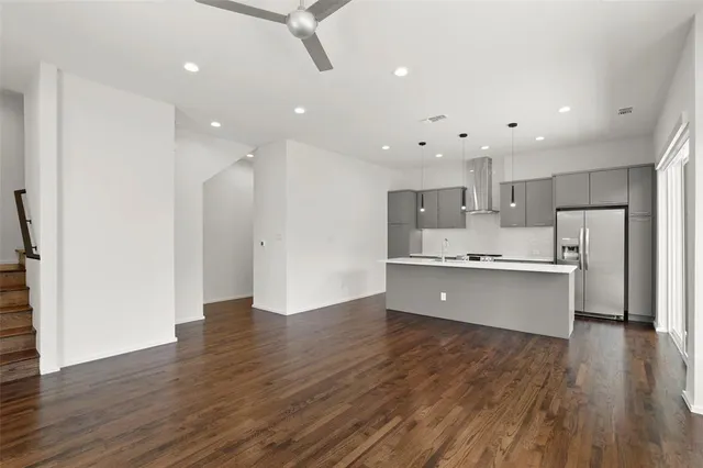 a large kitchen with a center island wooden floor stainless steel appliances and a window