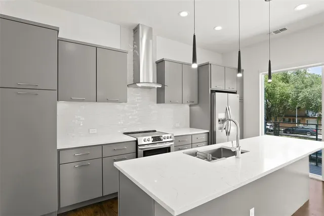 a kitchen with a white center island a refrigerator and a sink