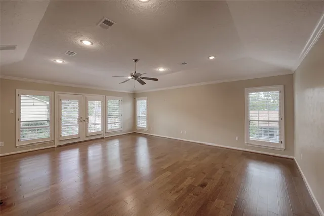 an empty room with wooden floor and windows