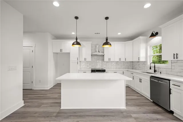 a kitchen with stove a sink dishwasher a refrigerator and a wooden floor