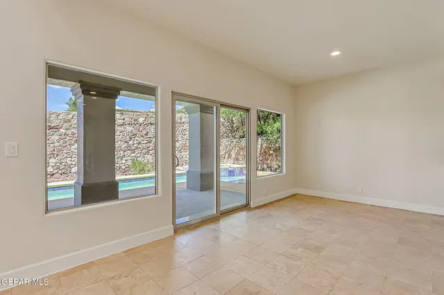 a view of an empty room with wooden floor and a ceiling fan