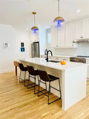 a large kitchen with stainless steel appliances a large counter top a stove and a sink