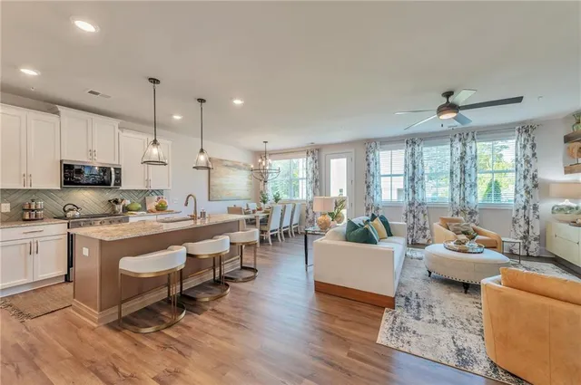 a living room with stainless steel appliances granite countertop furniture wooden floor and a view of kitchen