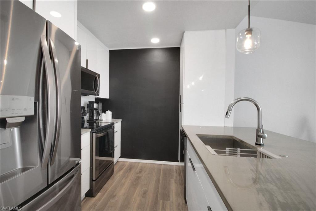 3342 Timberwood Circle Naples, FL 34105 - Photo 12 of 25 a kitchen with a refrigerator sink and stainless steel appliances
