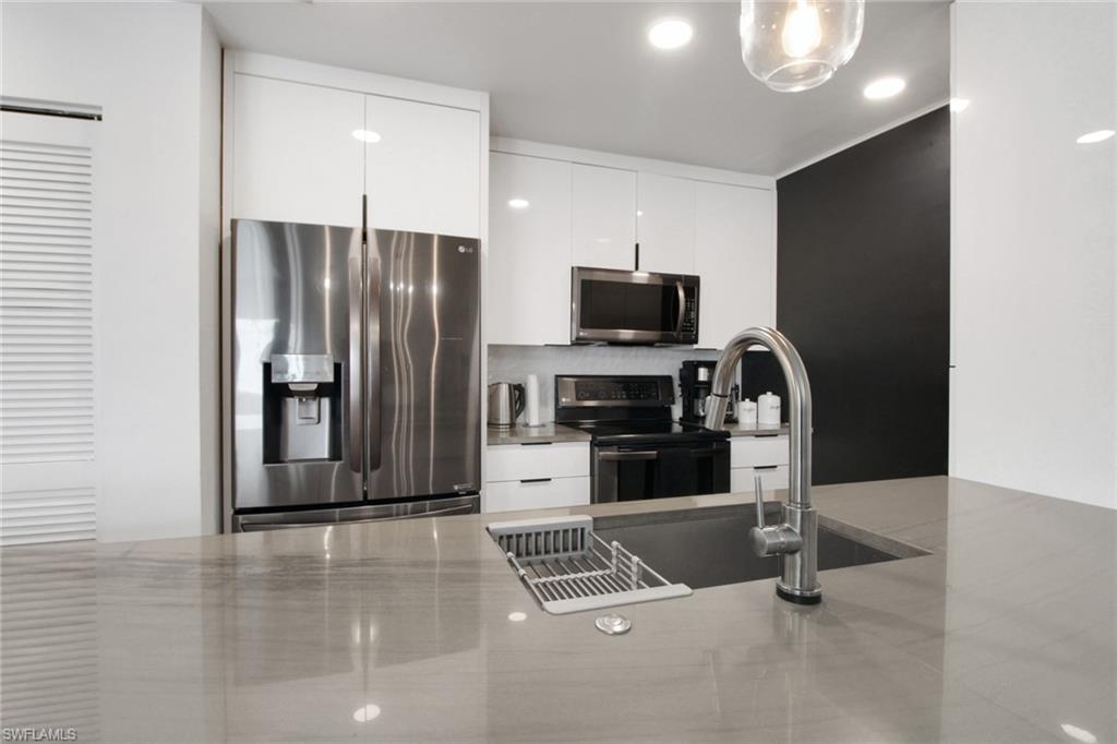 3342 Timberwood Circle Naples, FL 34105 - Photo 13 of 25 a kitchen with stainless steel appliances a refrigerator and a stove top oven