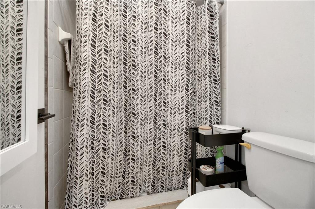 3342 Timberwood Circle Naples, FL 34105 - Photo 19 of 25 a white toilet sitting next to a shower curtain