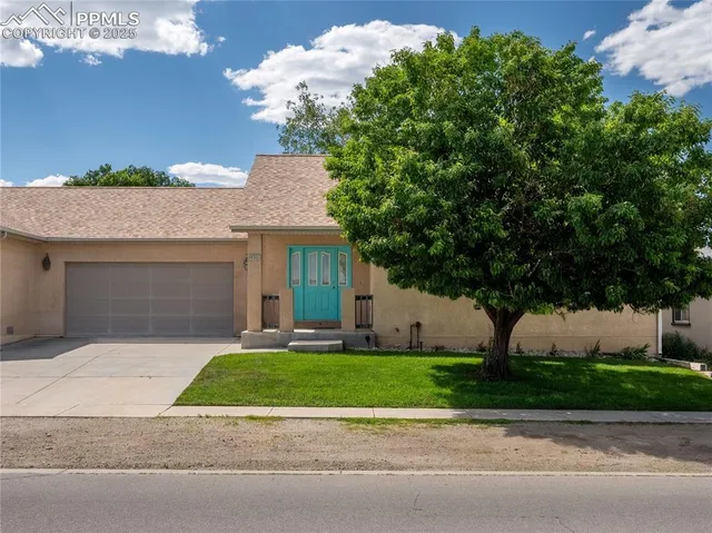 a front view of a house with a garden and a tree