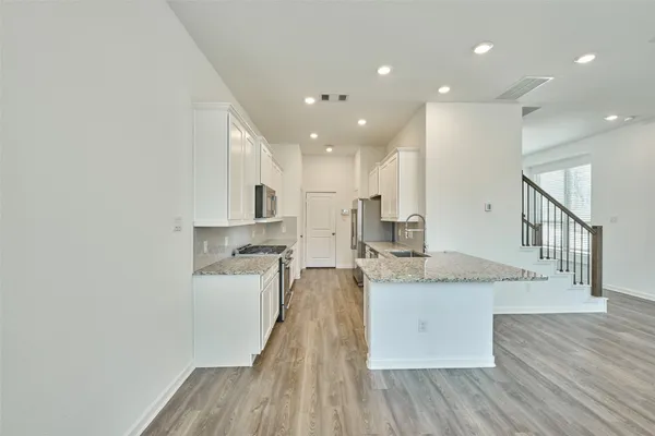 a large kitchen with granite countertop a large counter top a sink stainless steel appliances and cabinets