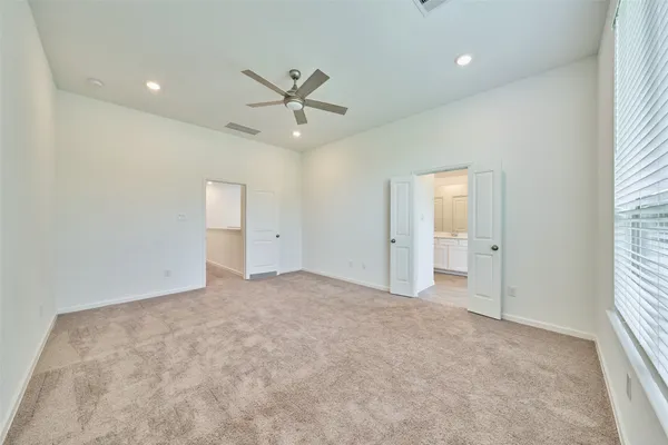 an empty room with windows and ceiling fan