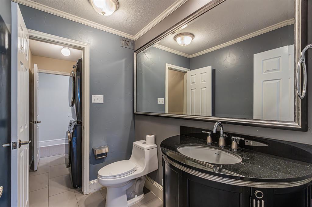 300 Sundance Circle Irving, TX 75063 - Photo 16 of 39 Bathroom featuring a curved vanity with a dark stone countertop and undermount sink, a large framed wall mirror, and a contemporary toilet