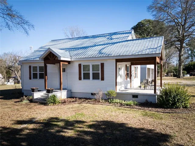 a front view of a house with a yard outdoor seating and covered with trees