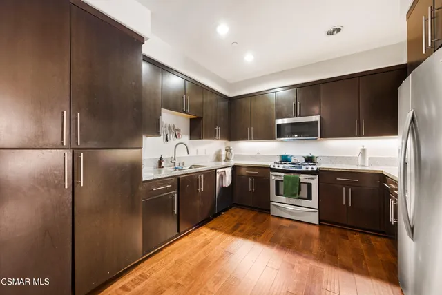 a large kitchen with stainless steel appliances granite countertop a refrigerator a stove top oven a sink and dishwasher