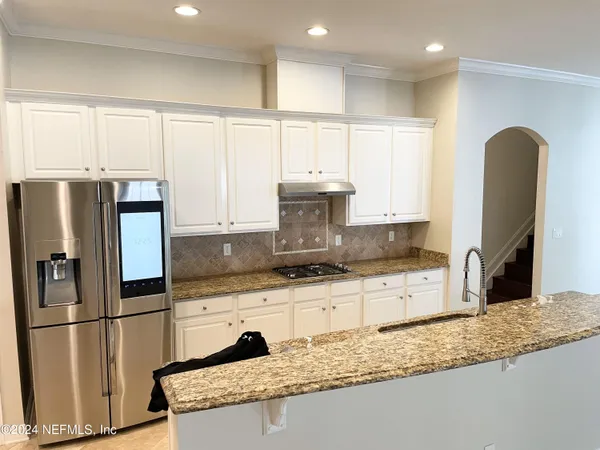 a kitchen with granite countertop a refrigerator a stove a sink and a microwave