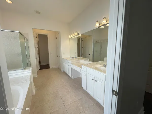 a bathroom with a double vanity sink a toilet a mirror and shower