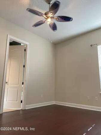 an empty room with wooden floor a ceiling fan and staircase