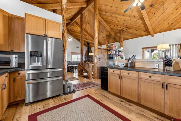 a kitchen with stainless steel appliances granite countertop a refrigerator a stove and a sink with wooden floor