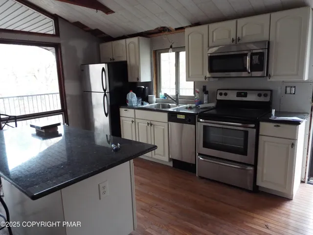 a kitchen with stainless steel appliances granite countertop a stove a refrigerator and a microwave