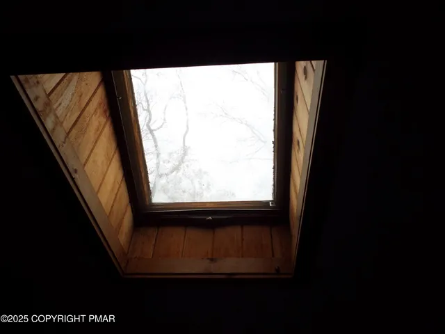an empty room with a chandelier fan and windows
