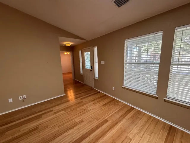 a view of an empty room with wooden floor and a window