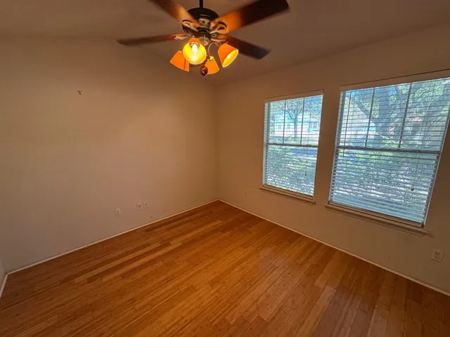 a view of an empty room with a window and wooden floor