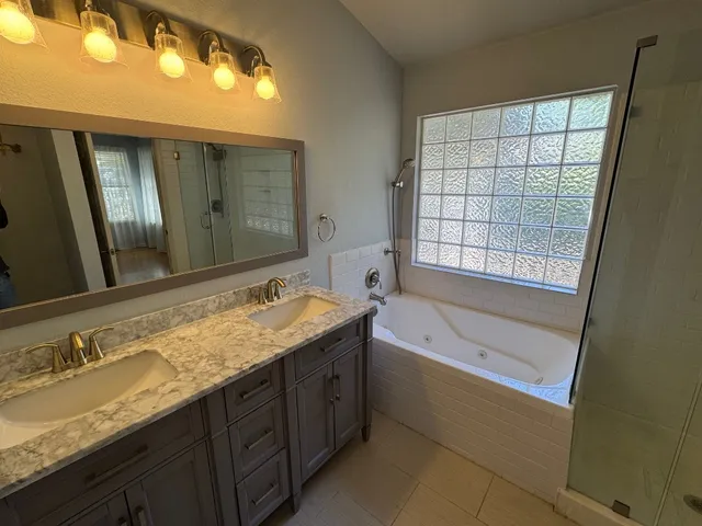 a bathroom with a granite countertop tub sink and mirror