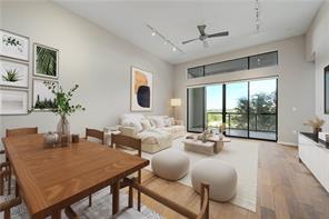 A spacious open-concept interior featuring warm wood floors and high ceilings with transom windows.