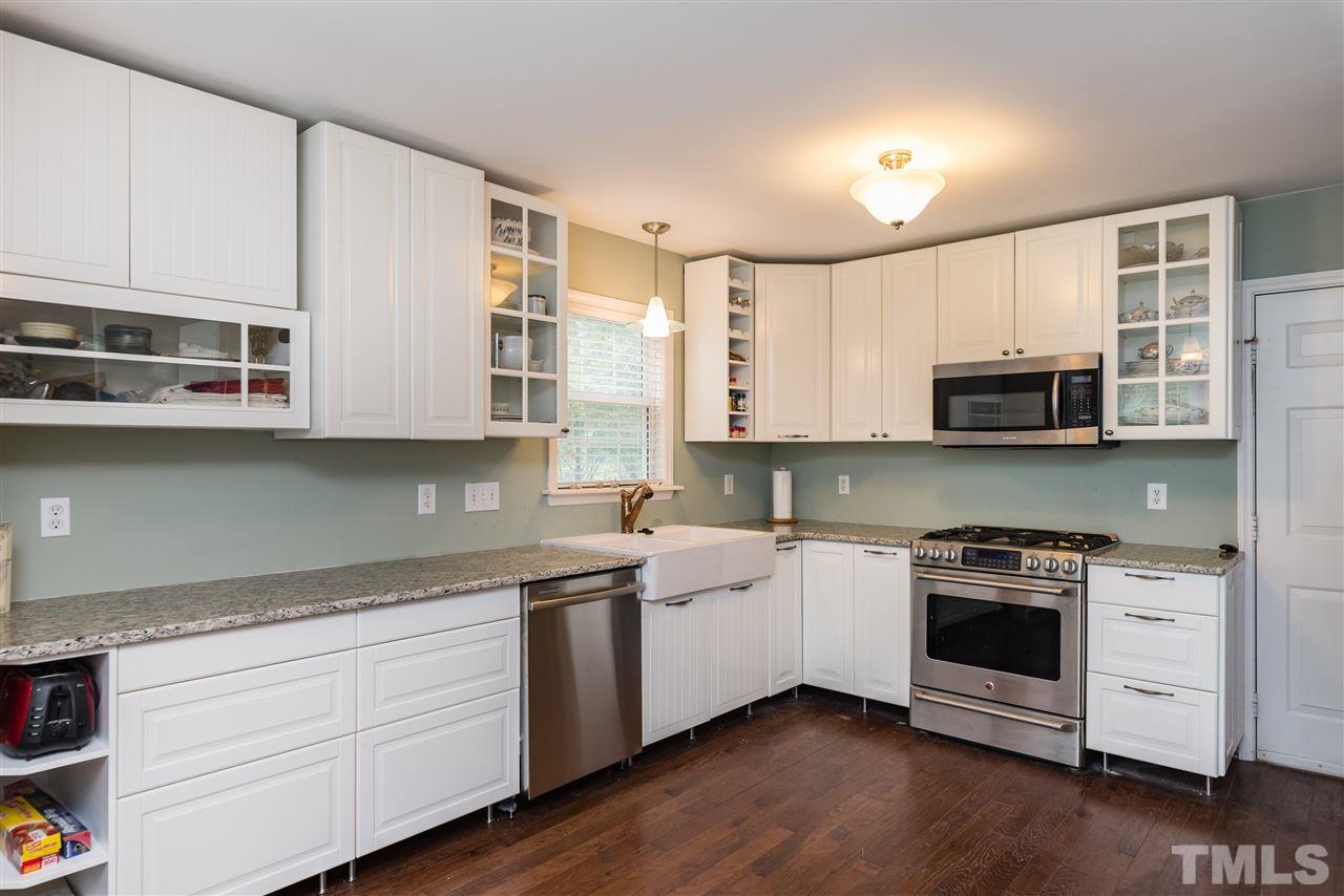 2305 Dahlgreen Road Raleigh, NC 27615 - Photo 7 of 19 a kitchen with stainless steel appliances granite countertop white cabinets a sink a stove a microwave and wooden floors