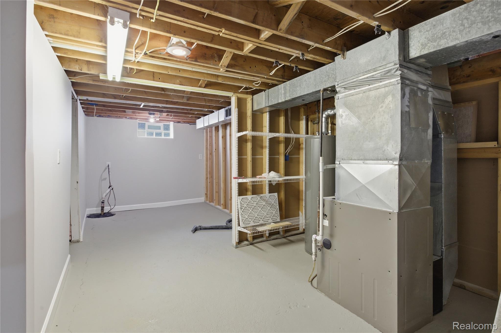 37257 Dundee Street Sterling Heights, MI 48310 - Photo 31 of 47 Unfinished lower level with exposed ceiling joists, painted concrete flooring, a block glass window, and a visible HVAC system
