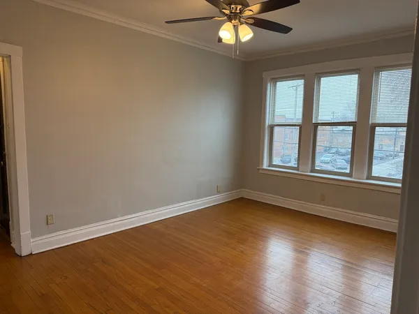 an empty room with wooden floor fan and windows