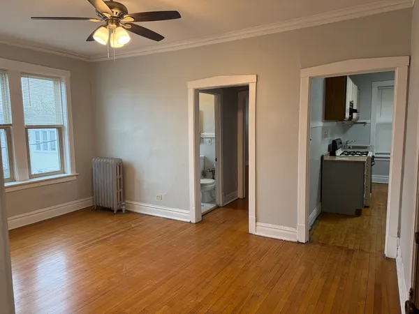 a view of an empty room with window and wooden floor