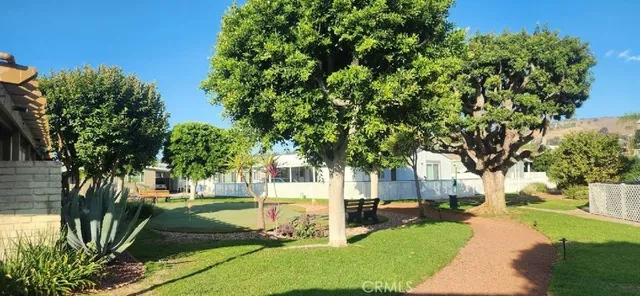 a view of a white house with a big yard and large trees