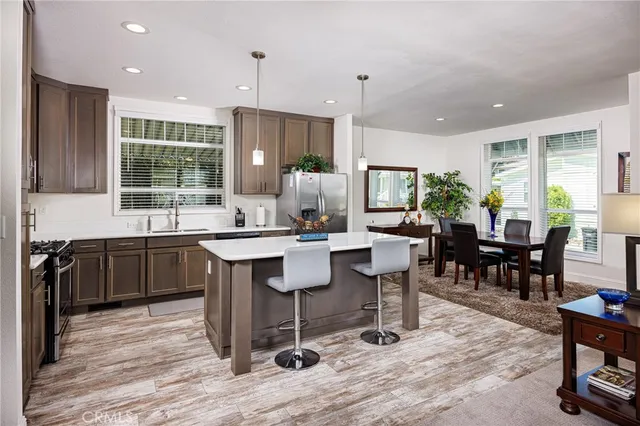 a kitchen with a dining table chairs cabinets wooden floor and appliances