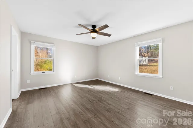a view of an empty room with window and wooden floor
